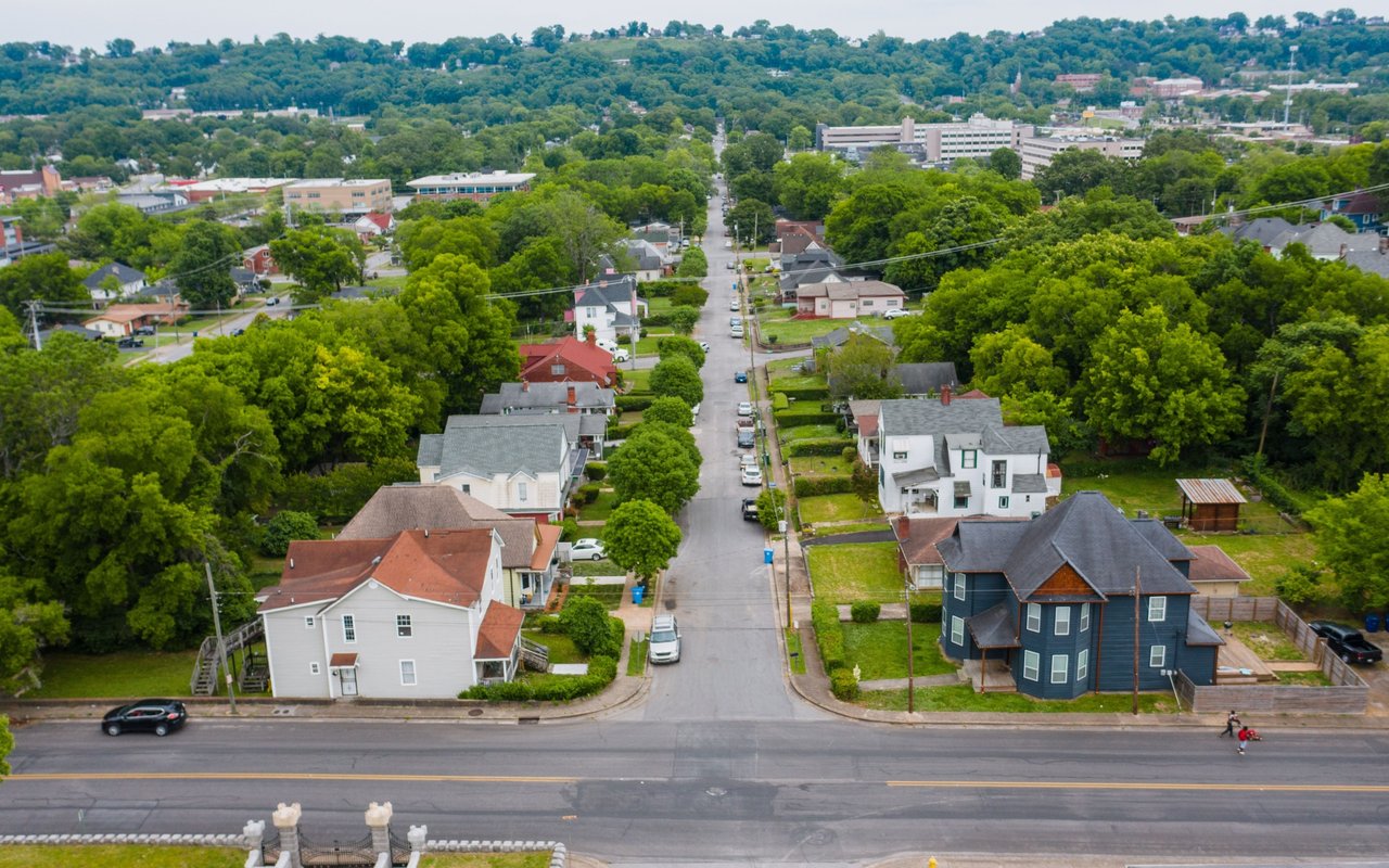 Aerial view of Culebra homes along a tree-lined street, with wooded hills in the distance.
