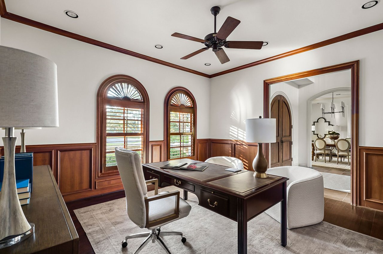 Home office with wood paneling, built-in desk, and arched windows at 5902 Saratoga Cove, Davenport Ranch, Austin, Texas.