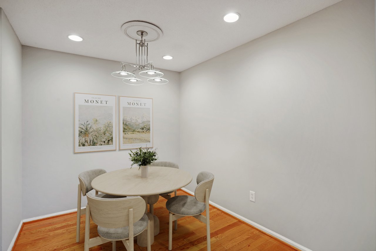 Dining area with a round table, upholstered chairs, Monet prints, and hardwood floors.