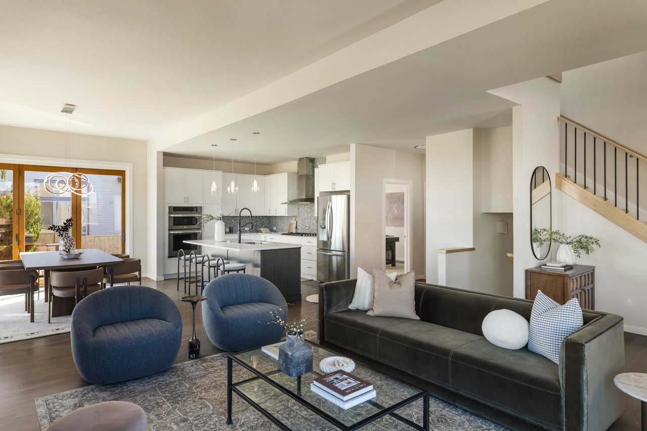 Open living area with navy swivel chairs and a sofa, with the kitchen and dining area beyond