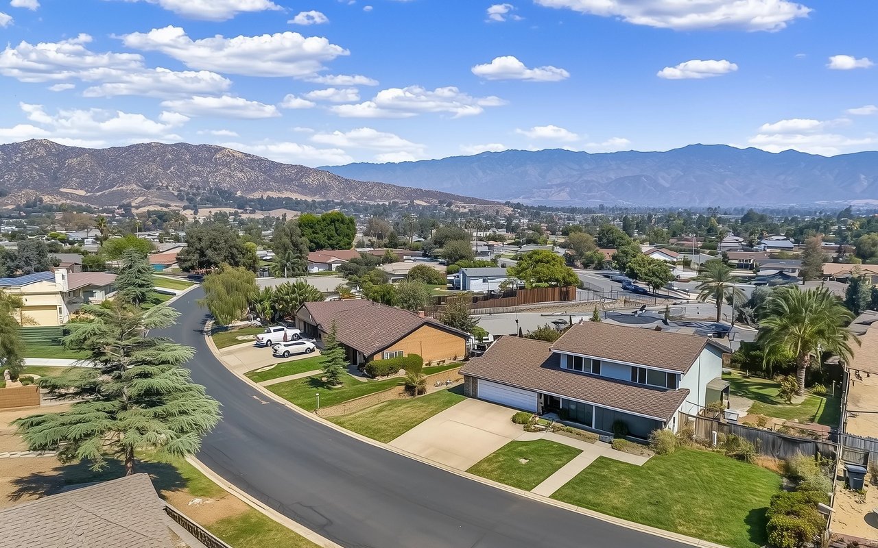 Aerial view of Avocado Heights homes and curving streets, with mountain ranges in the distance.