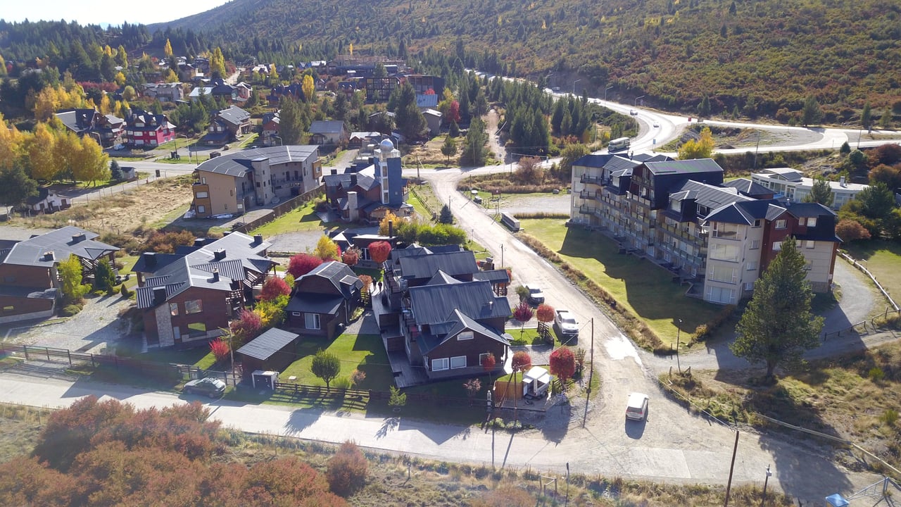 Hillside neighborhood of chalet-style homes and apartment buildings surrounded by autumn-colored mountains.