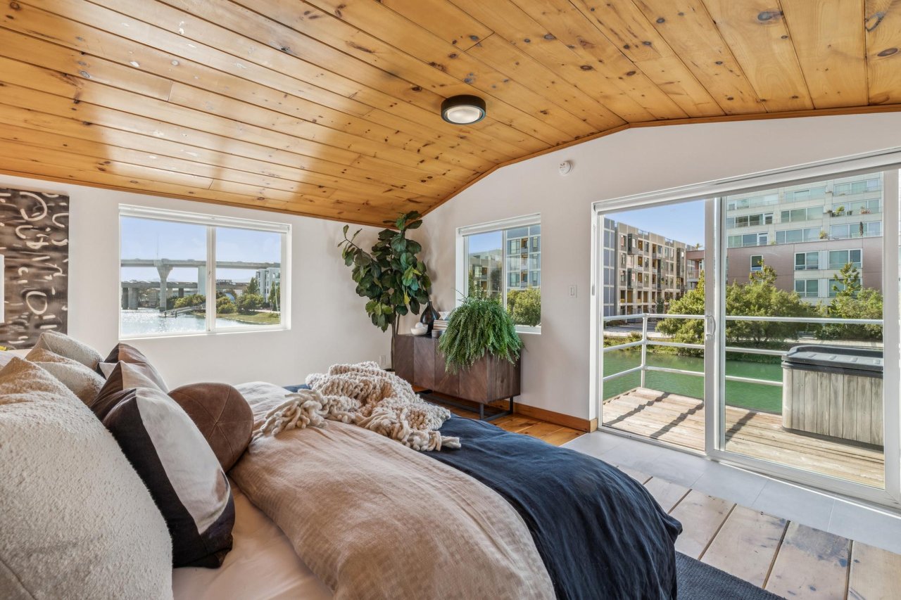 Bedroom with a knotty wood ceiling, balcony, and waterway view.