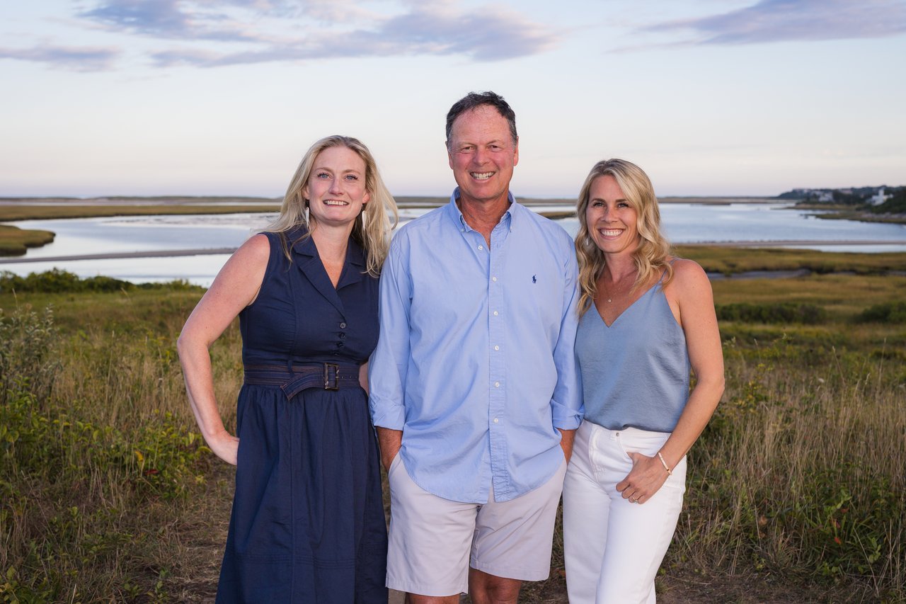 Three Cape Island Estates agents pose together in a coastal marsh beside tidal water.