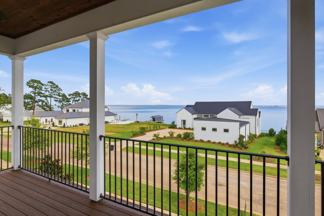 Water view from a covered balcony overlooking neighboring homes and landscaped lawns.