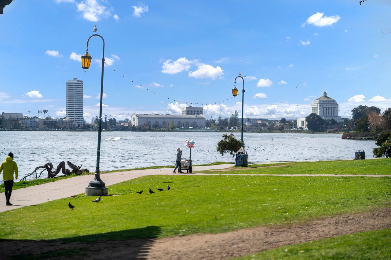 Lake Merritt and Oakland buildings viewed from the grassy lakeside park.