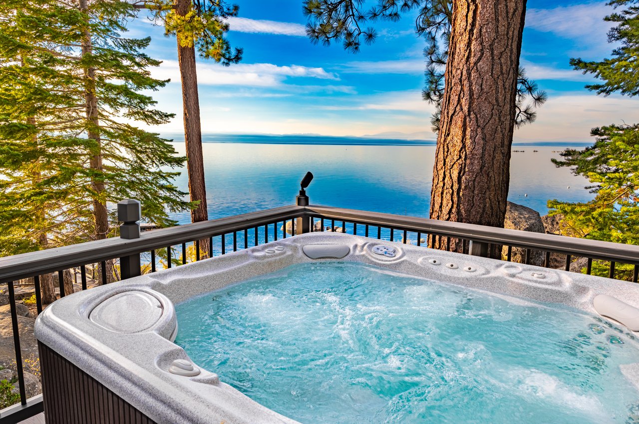 Outdoor hot tub overlooking the lake, framed by tall pine trees.