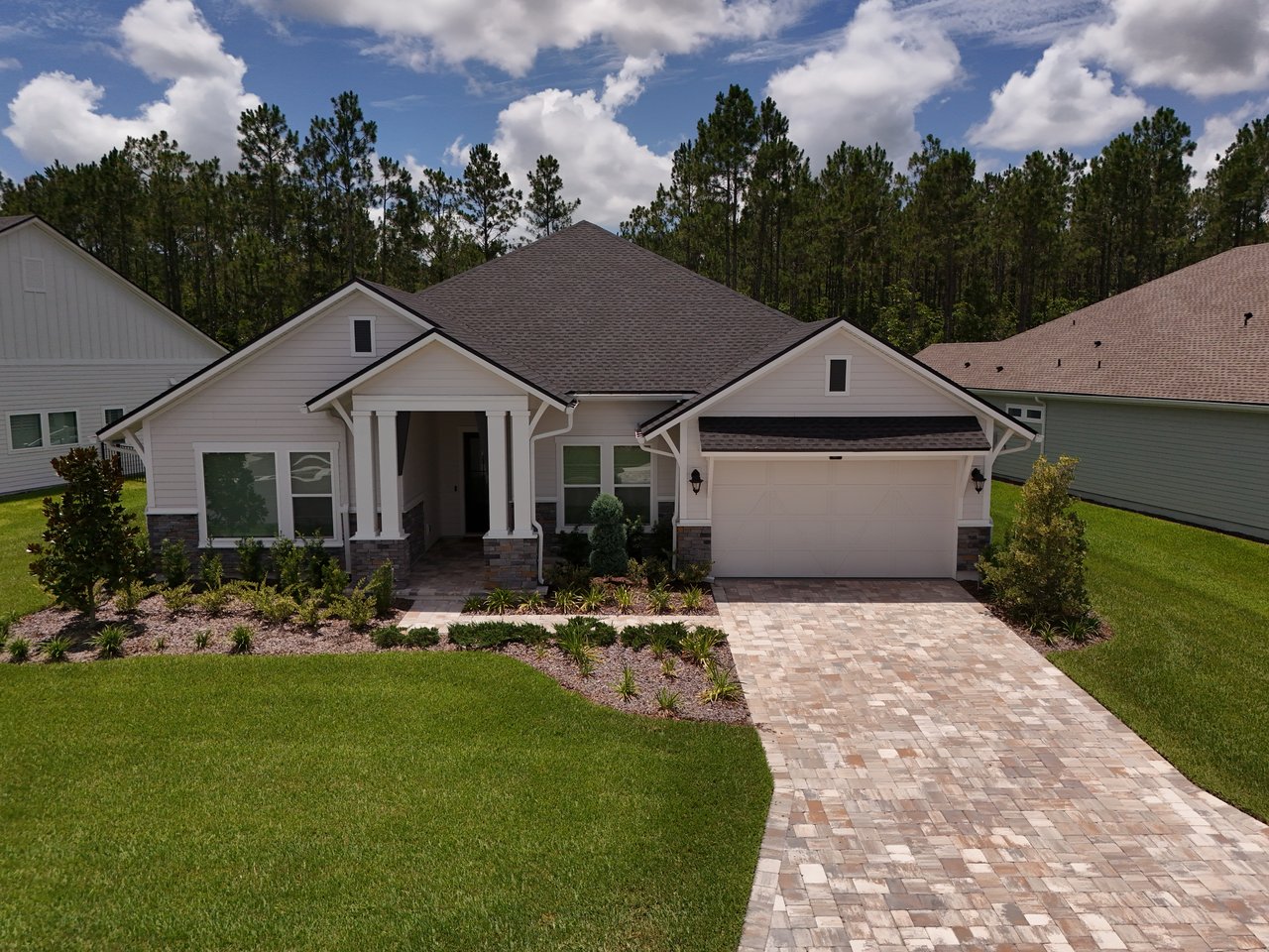 Single-story home with a covered entrance, attached garage, and wide paver driveway.