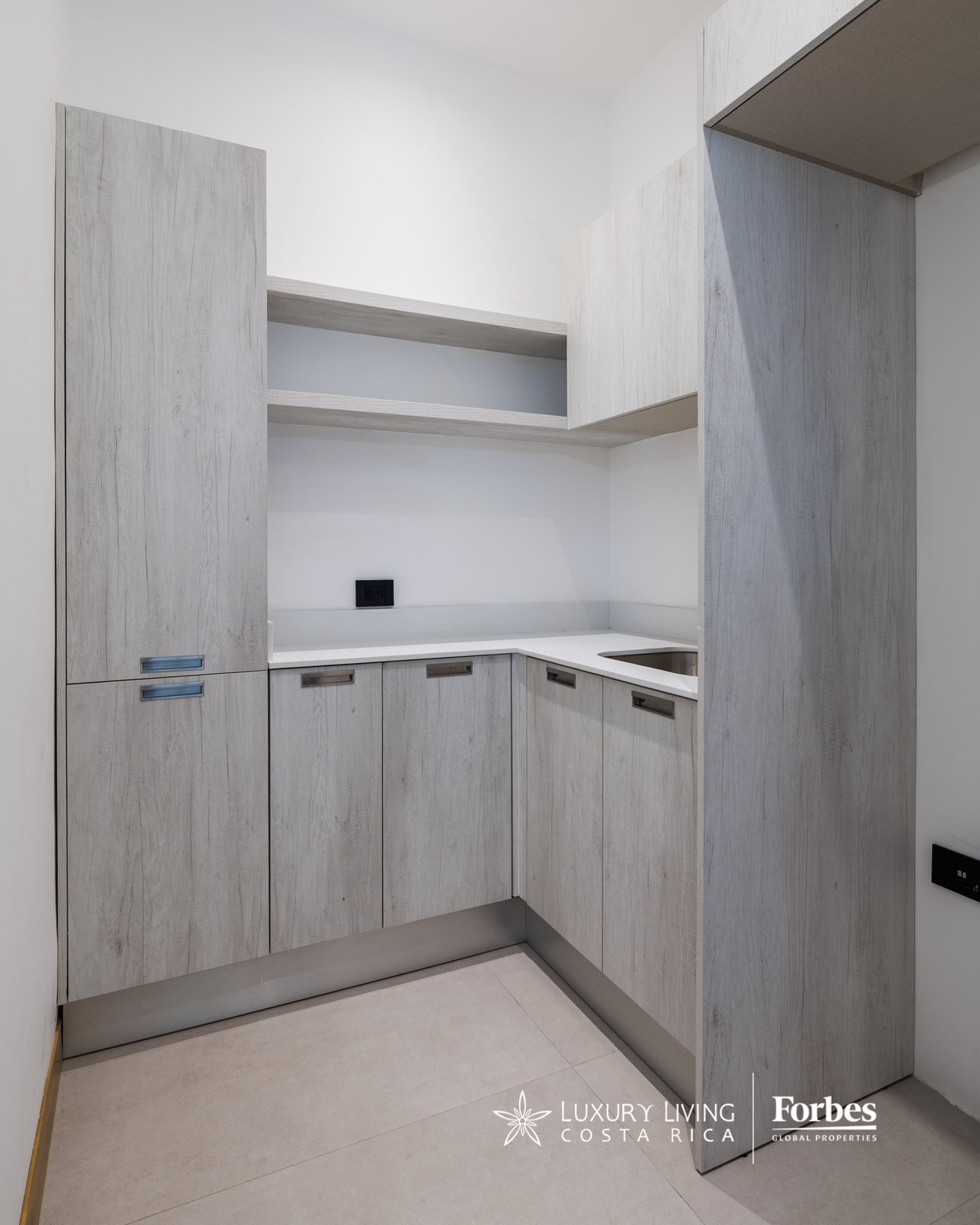 Built-in kitchen with pale wood cabinets, white counters, and an inset sink.