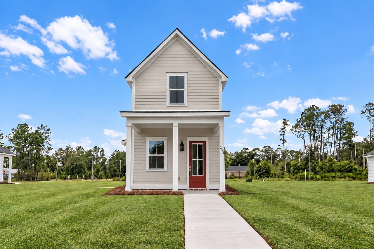 Two-story light-sided home with a steep gable, covered porch, red door, and walkway.