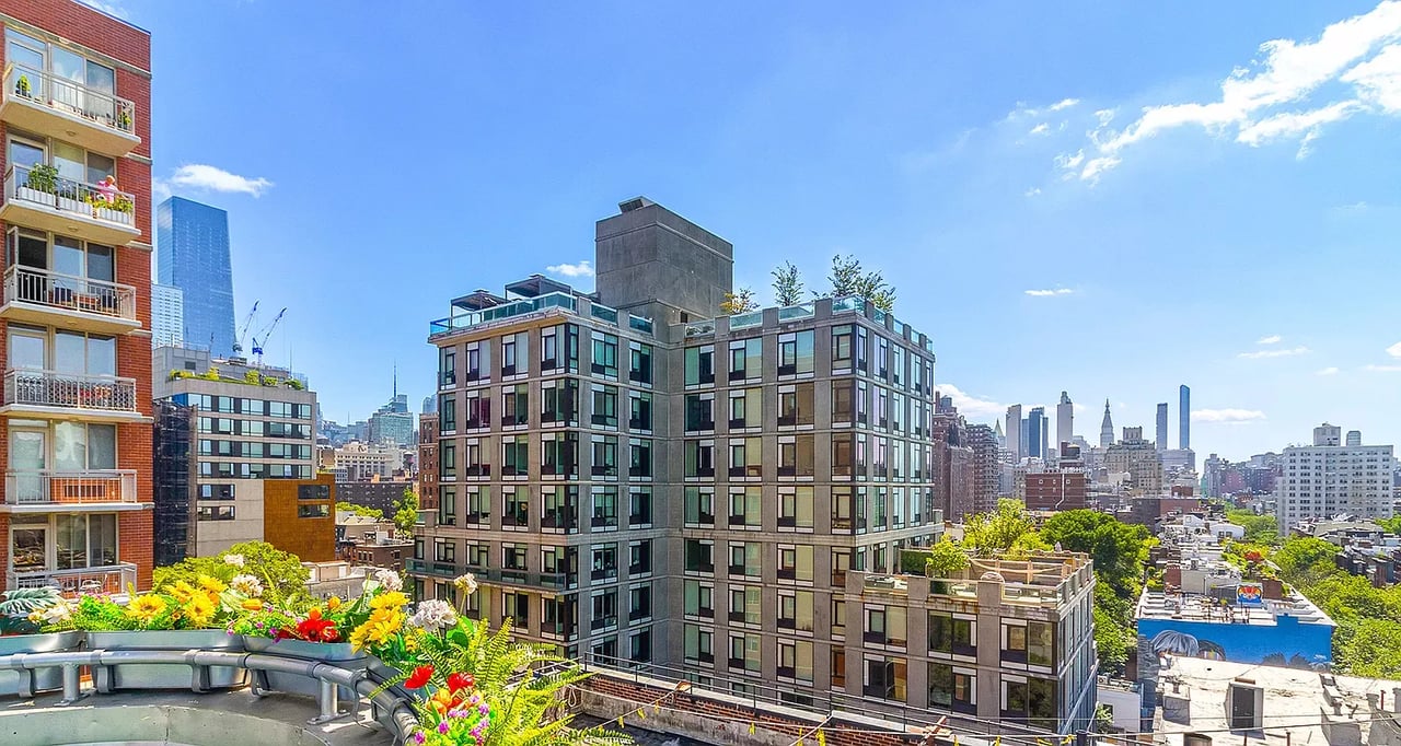 NYC apartment buildings and city skyline view from a rooftop on a sunny day.