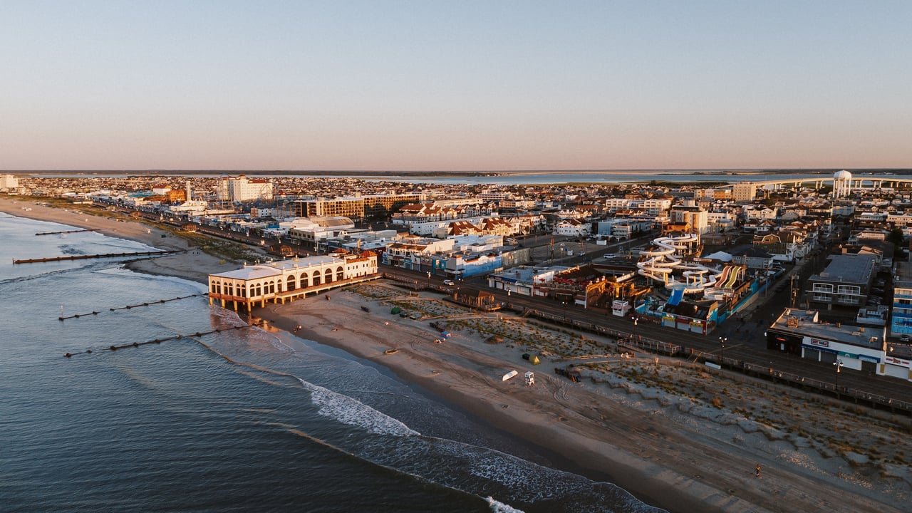 Aerial view of a beachfront town with a boardwalk and water slides beside the ocean.
