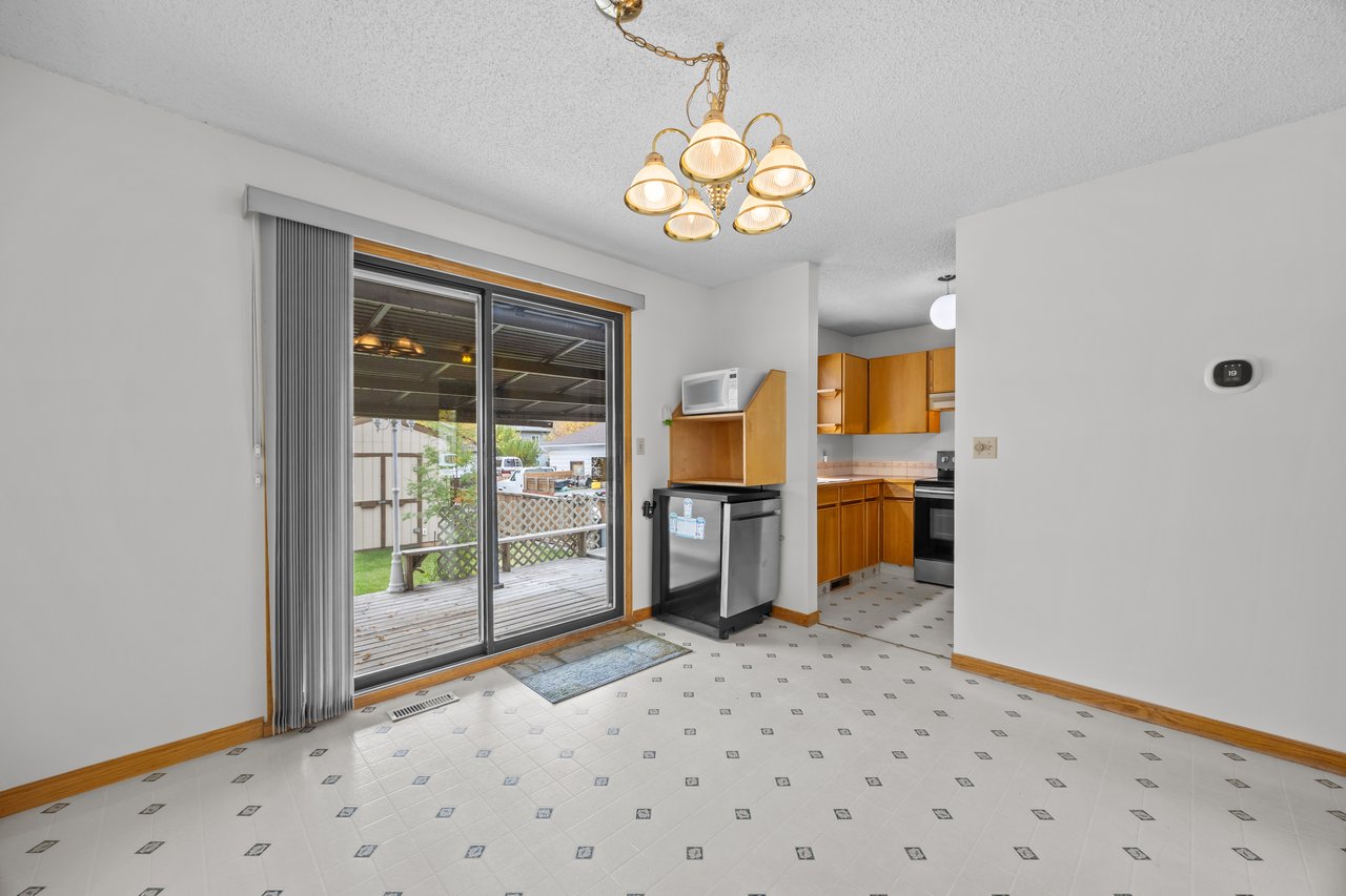 Kitchen with wood cabinets and patterned tile flooring beside a sliding glass door to the deck.