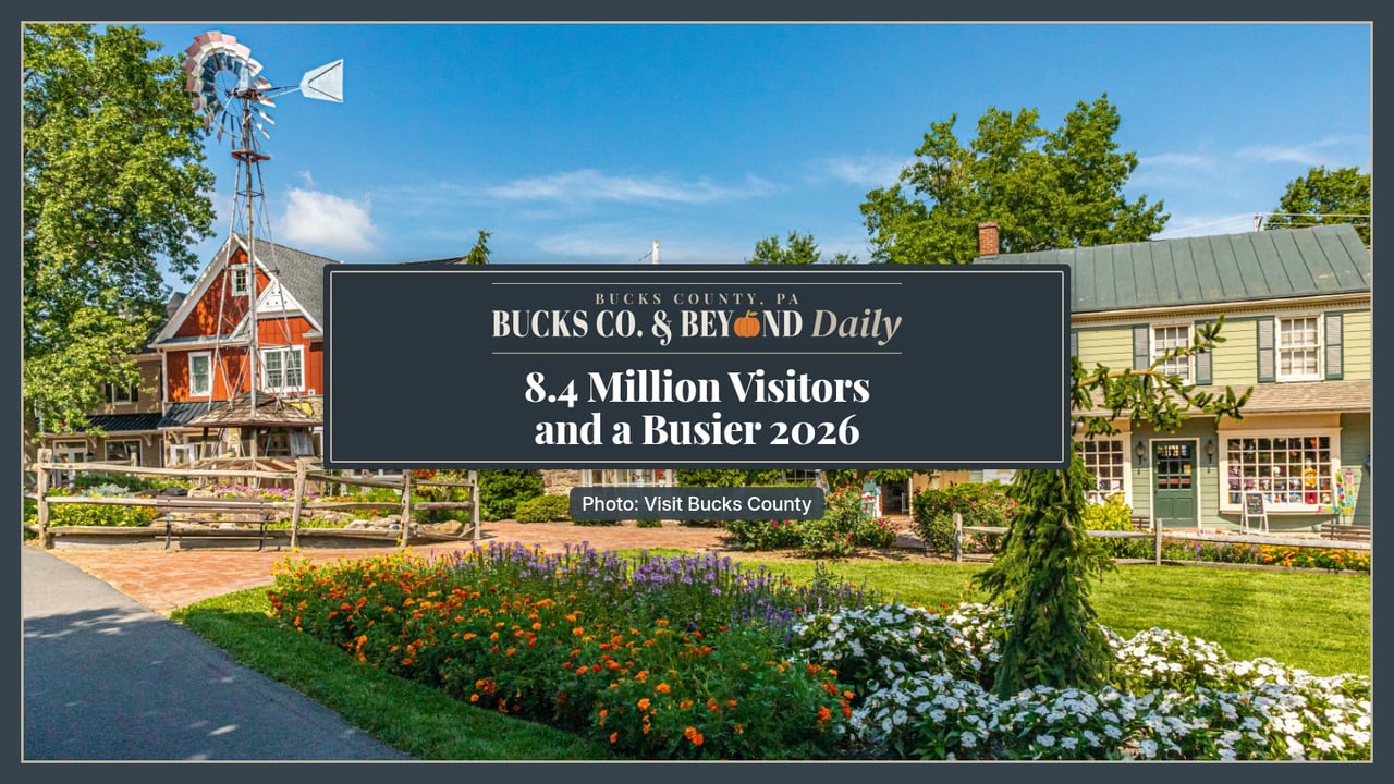 Bucks Co. & Beyond Daily: 8.4 Million Visitors and a Busier 2026. Peddler's Village in Lahaska on a sunny summer day, with a red barn-style shop, a windmill and a green clapboard shop behind beds of orange, purple and white flowers.
