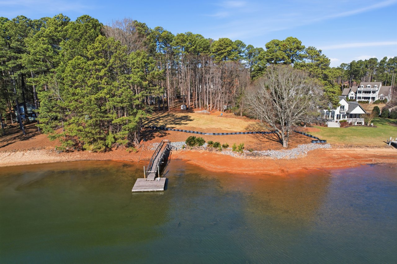 lake norman from the lake facing towards a large luxury lot, cleared towards the water and trees at the back and a floating dock at the front