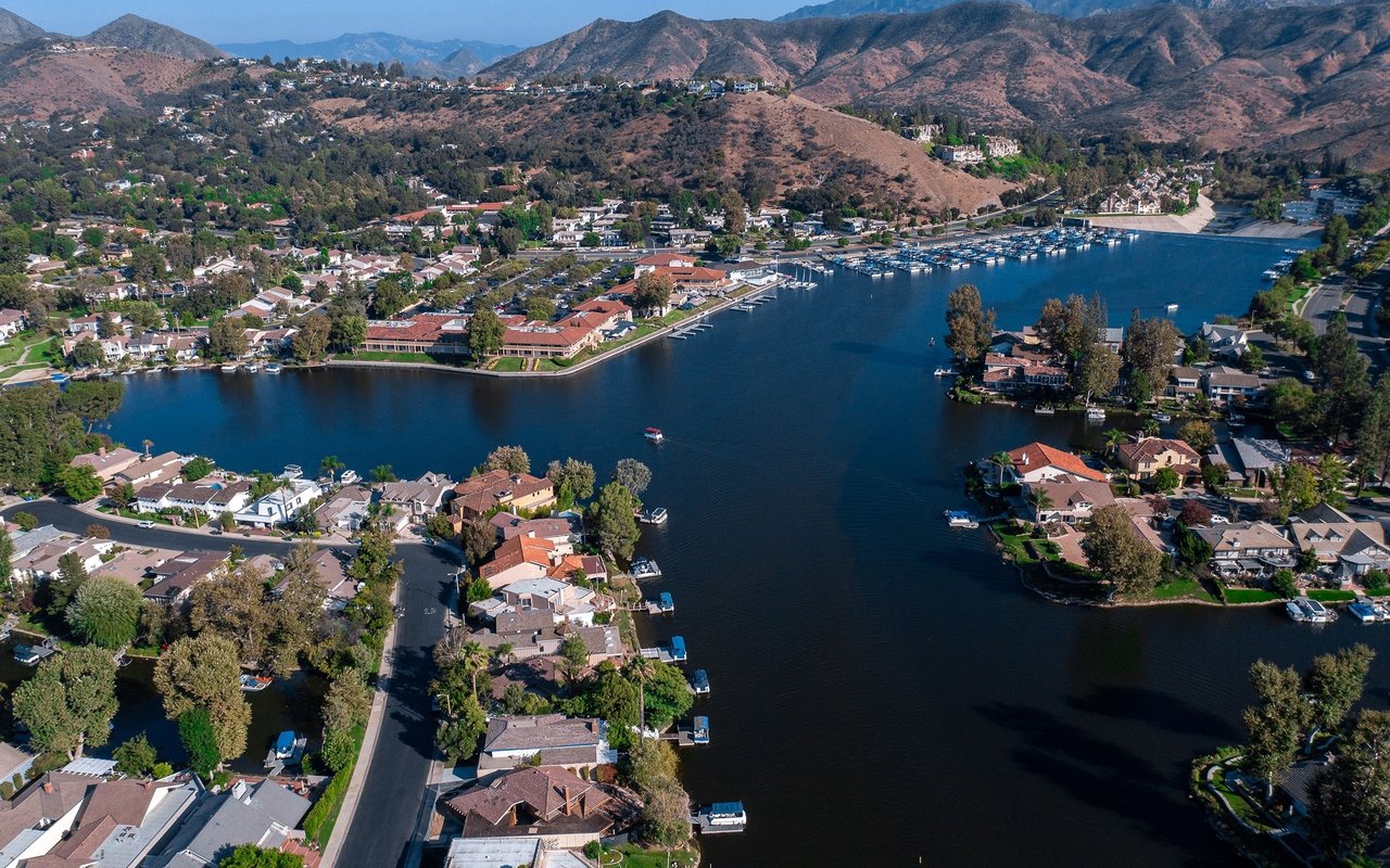 Waterfront neighborhood with lakeside homes, a marina, and dry hills beyond.