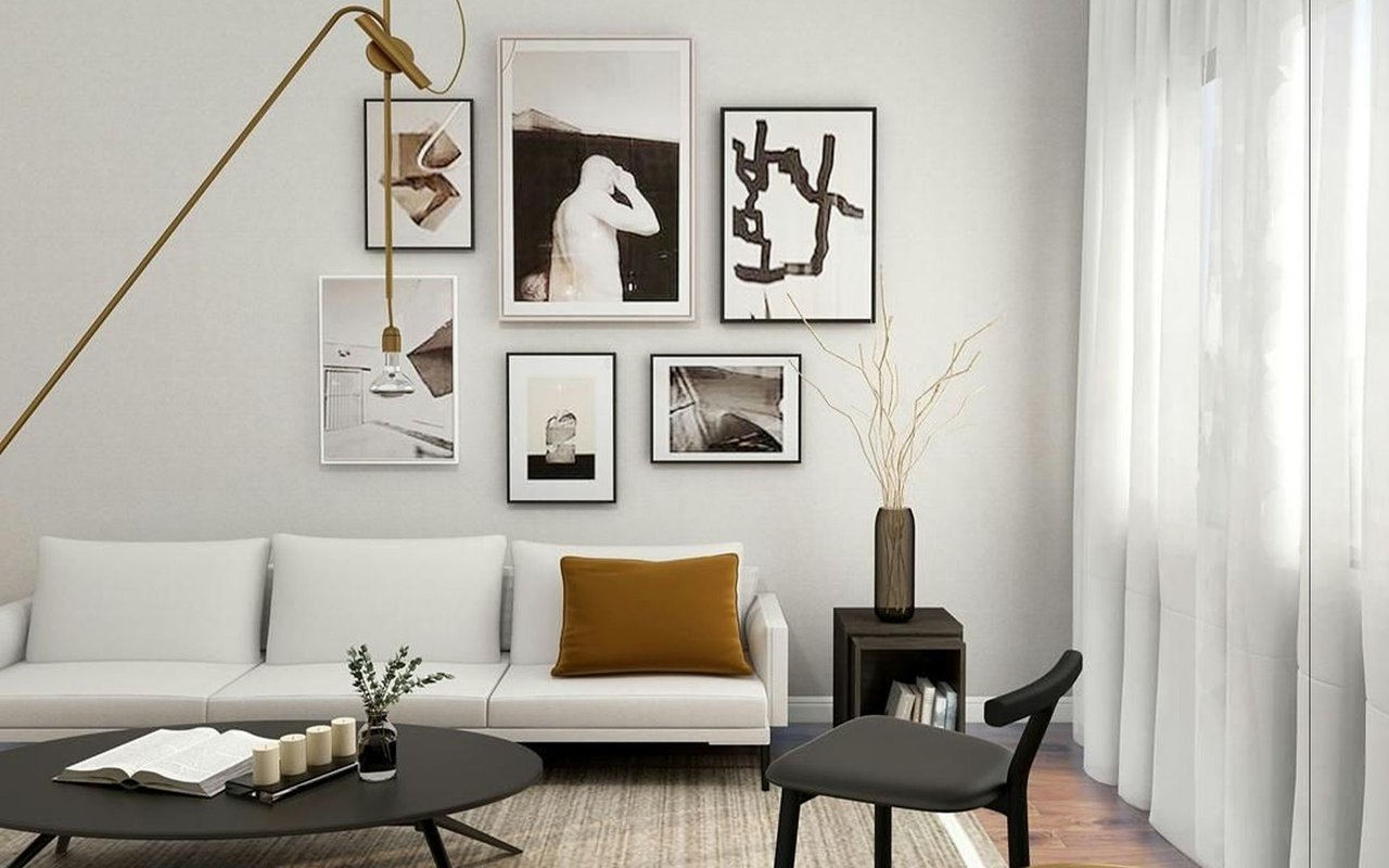 Living room with a white sofa, mustard pillow, gallery wall, and sheer curtains.