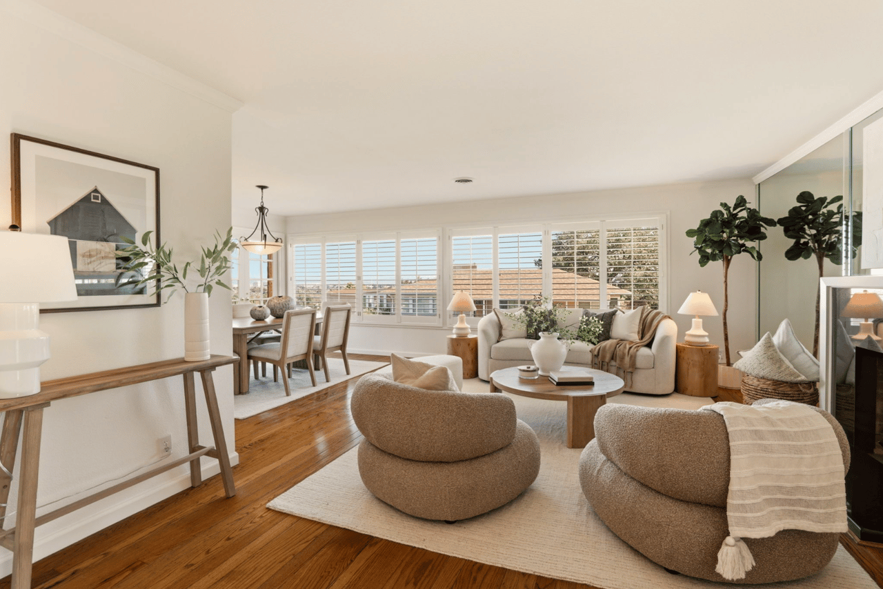 Bright living and dining room with hardwood floors and wide shuttered windows.