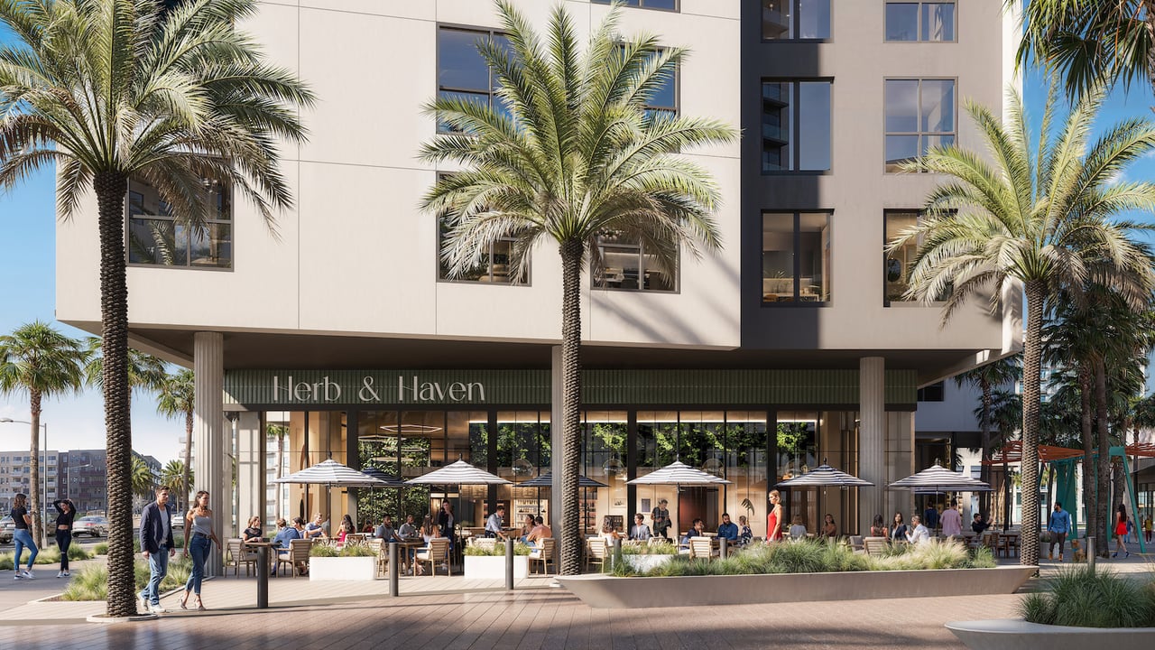 Cello Tower’s modern exterior with palm trees and the Herb & Haven restaurant patio.