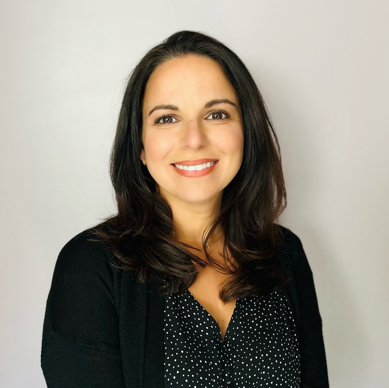 Sevi Sehnert smiling in a black cardigan and dotted blouse