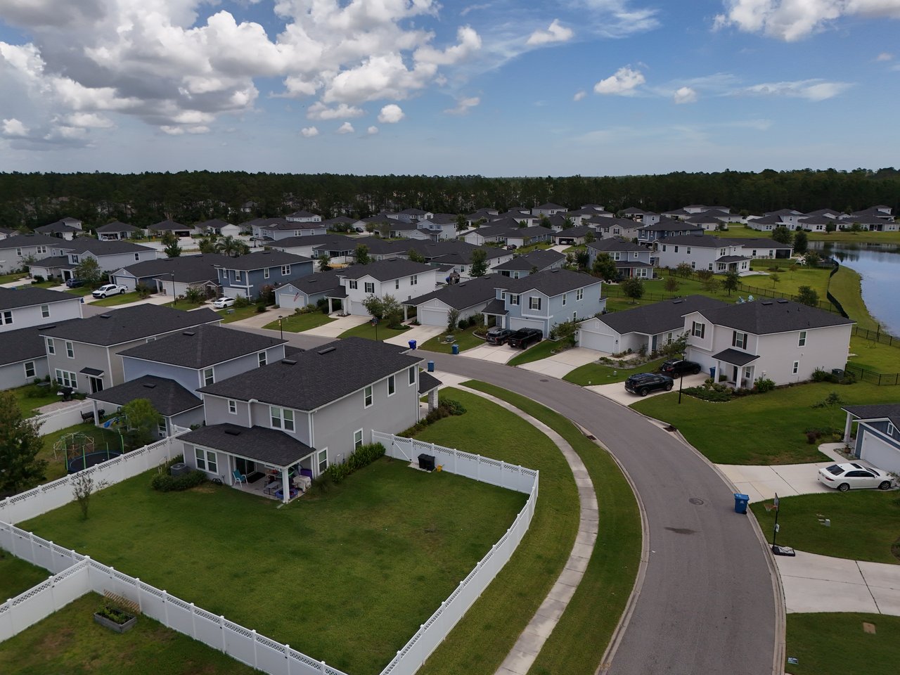 Aerial view of Meadow Ridge homes, curving streets, fenced yards, and a pond.