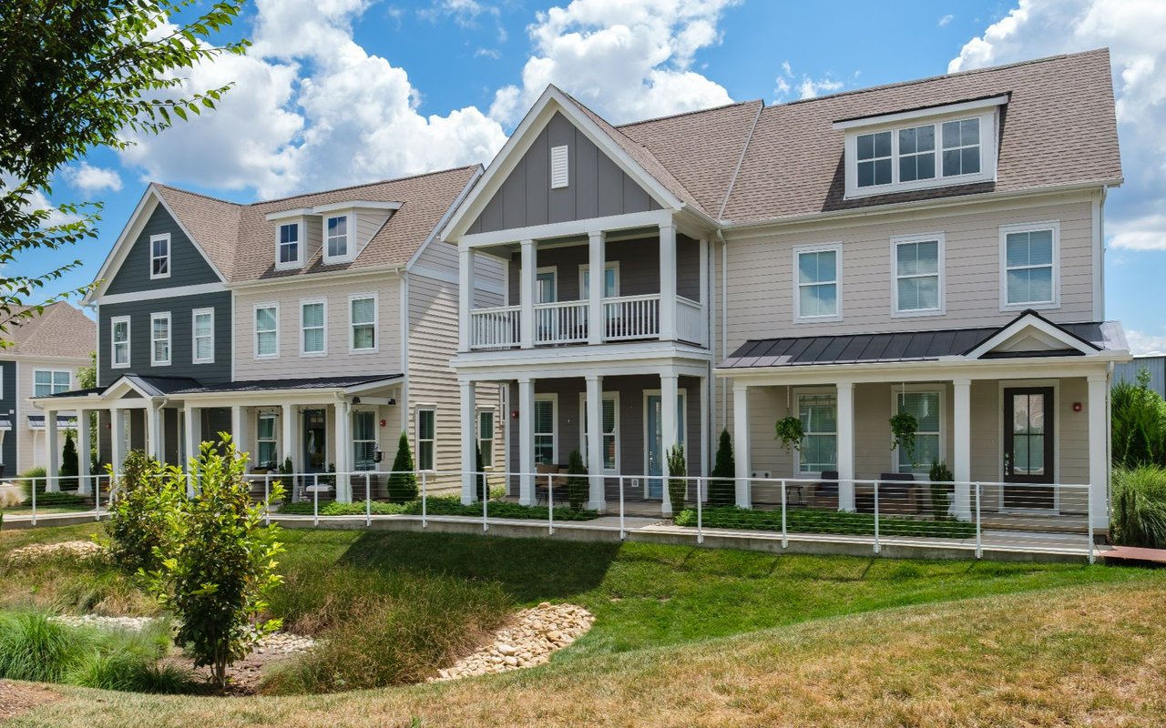Two-story attached homes with covered porches, white railings, and landscaped front lawns.
