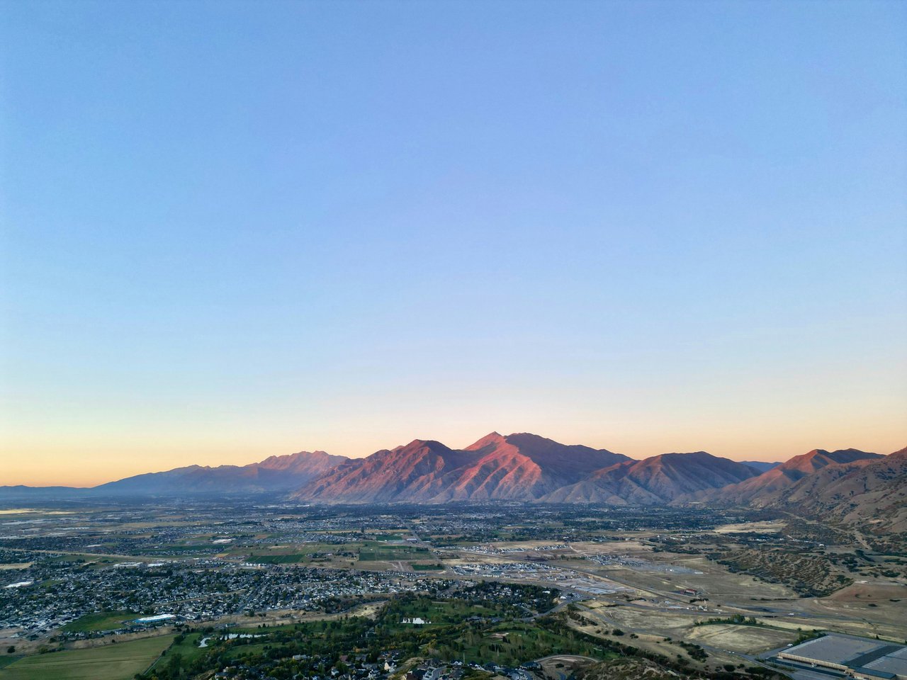 Aerial view of Utah Valley neighborhoods and homes at sunset with the Wasatch Mountains glowing in the background