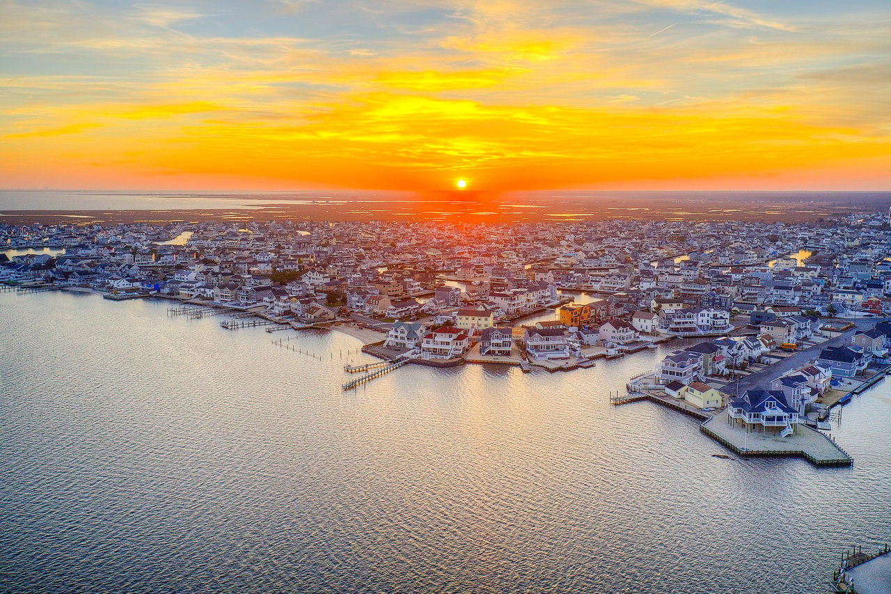 Aerial view of waterfront homes and docks at sunset, surrounded by calm water.