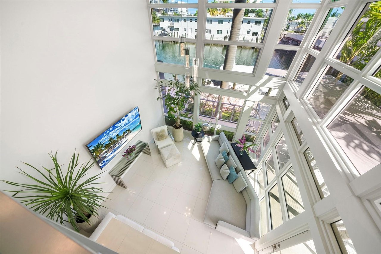 Double-height living room with floor-to-ceiling windows overlooking a canal.