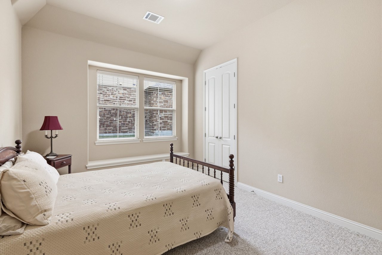 Bedroom with a large bed, burgundy bedside lamp, two windows, and white double doors.