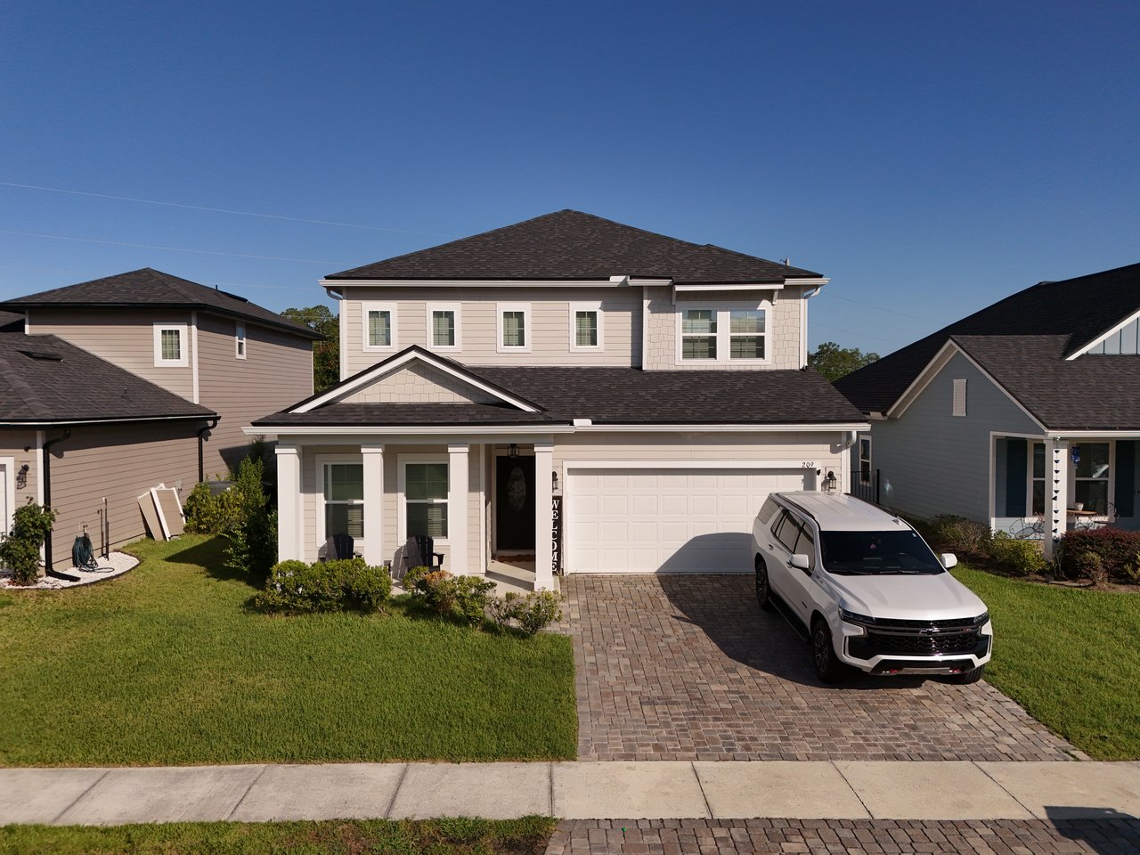 Two-story home with a covered porch, two-car garage, and white SUV in the driveway.