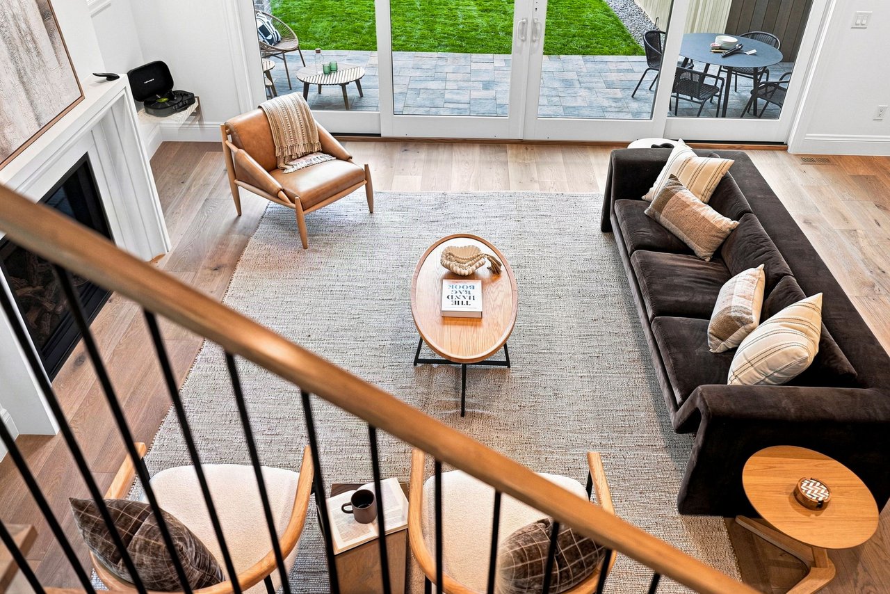 Staged living room with a fireplace, dark sofa, and glass doors opening to a patio and lawn.