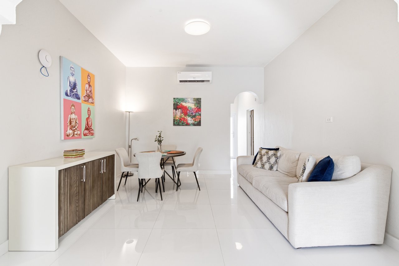 Furnished living and dining room with a white sofa and round dining table.