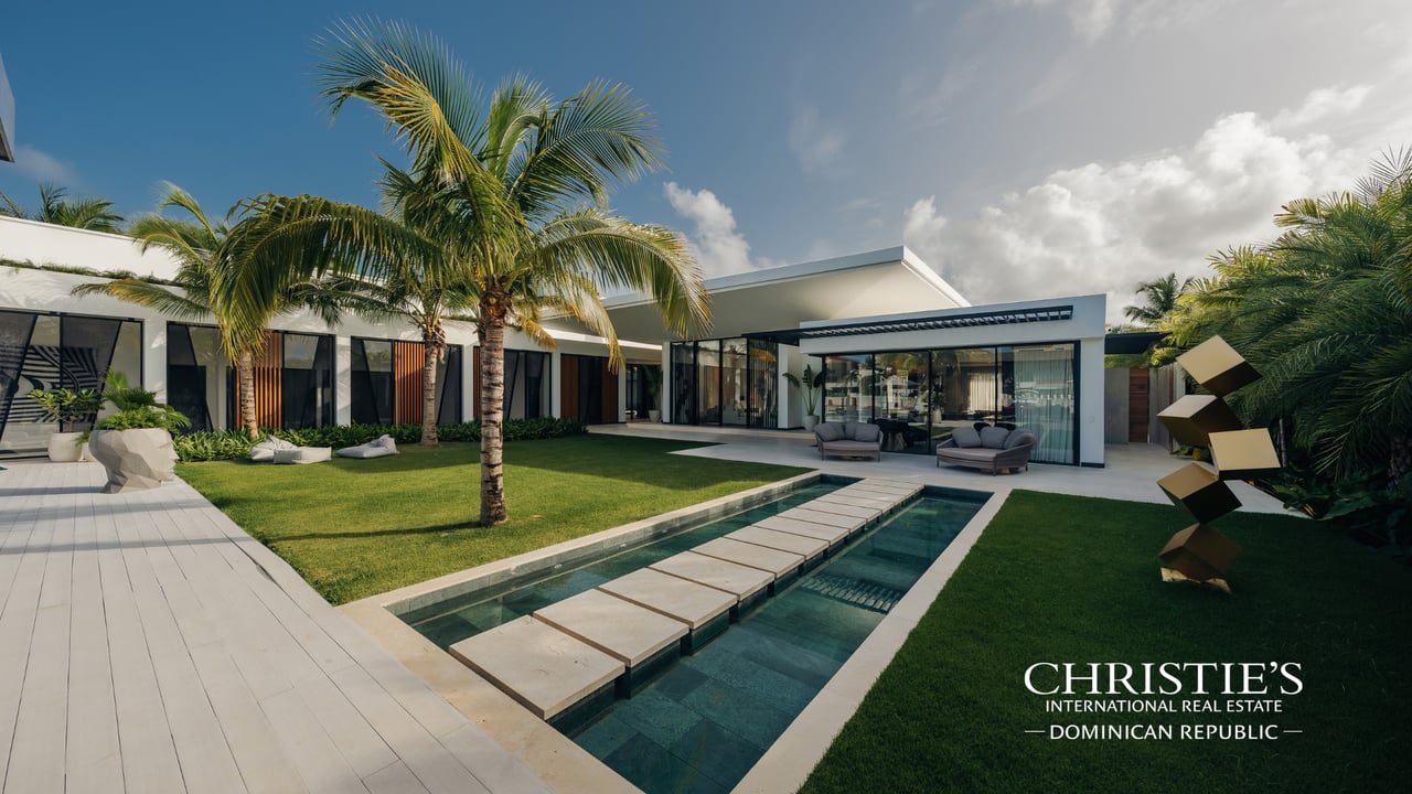 Modern Cap Cana villa with a courtyard pool, stepping-stone path, and palm trees.