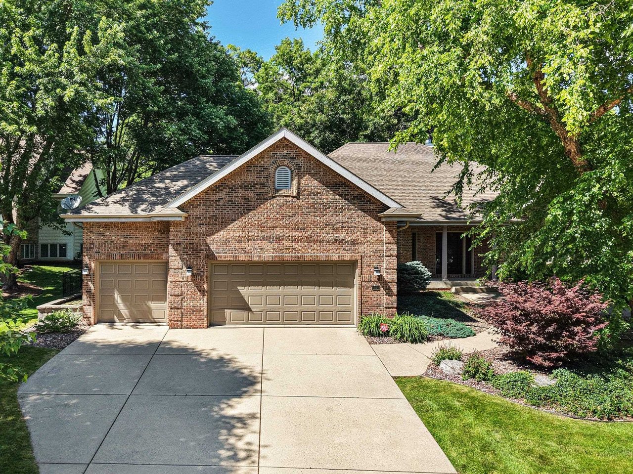 A well-kept brick home with an attached garage and mature trees on a sunny day in an established Madison, Wisconsin neighborhood.
