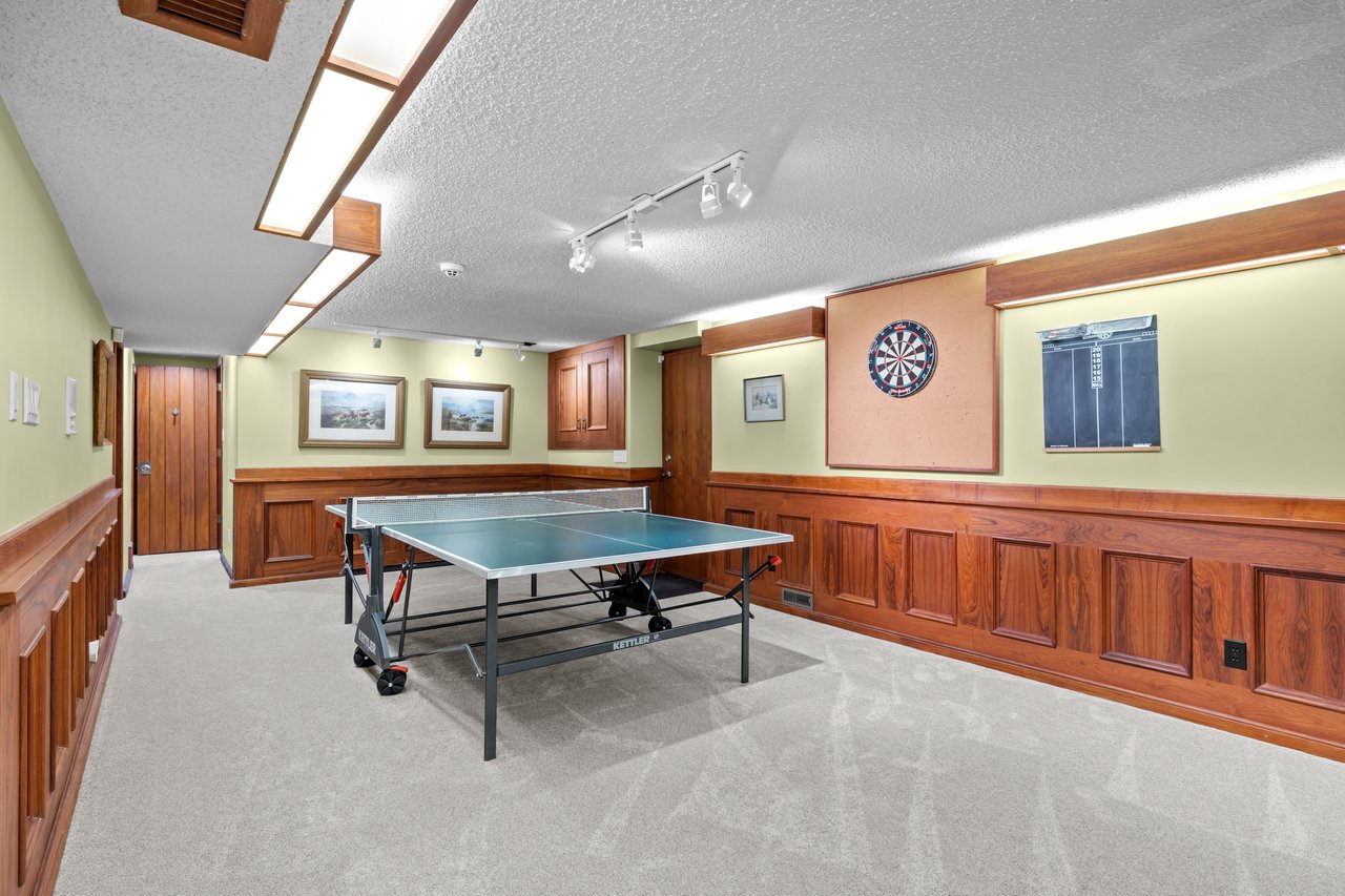 Game room with a table tennis table, wood-paneled walls and a dartboard.