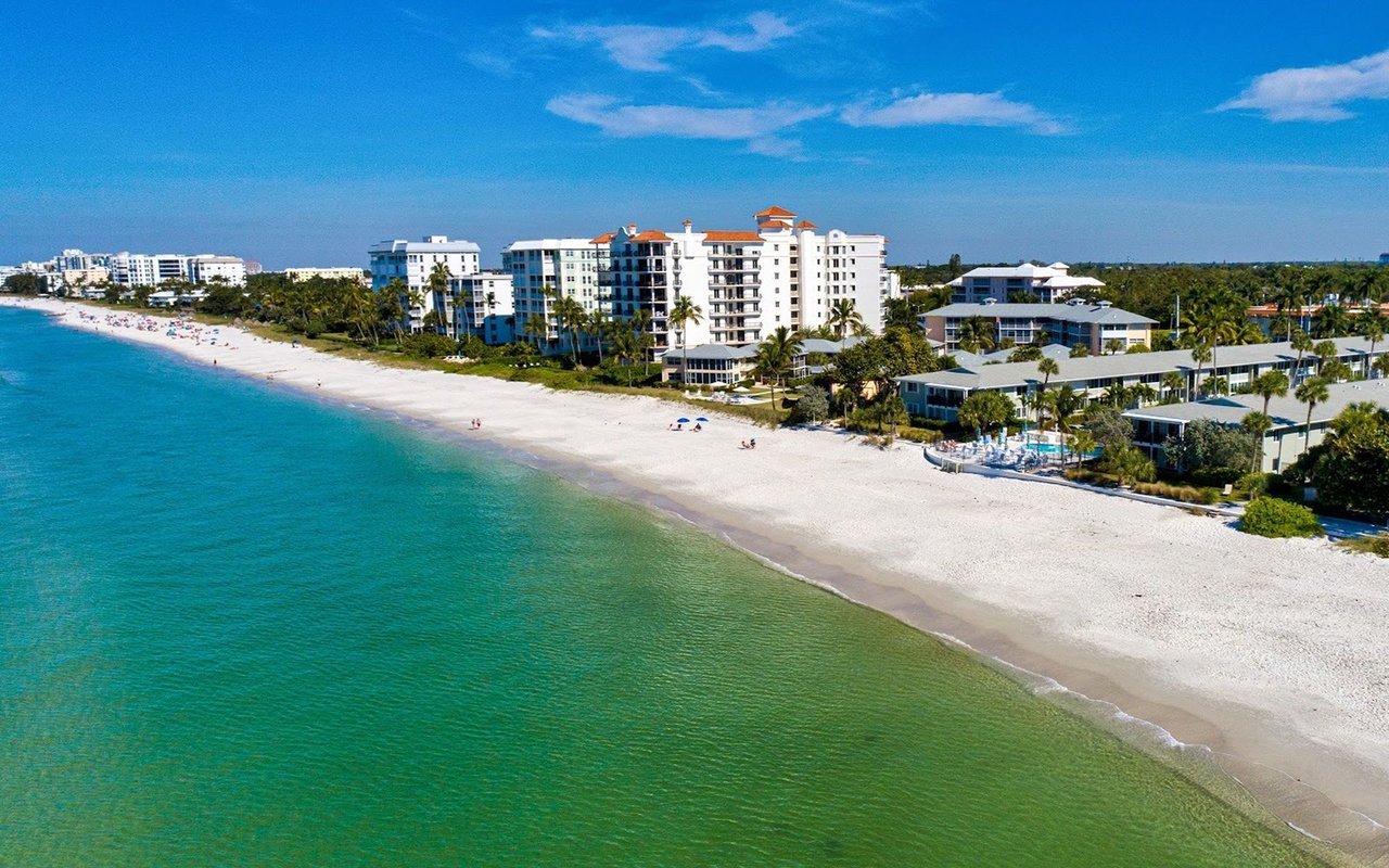 Coquina Sands beachfront with turquoise water, white sand, and coastal condominiums.