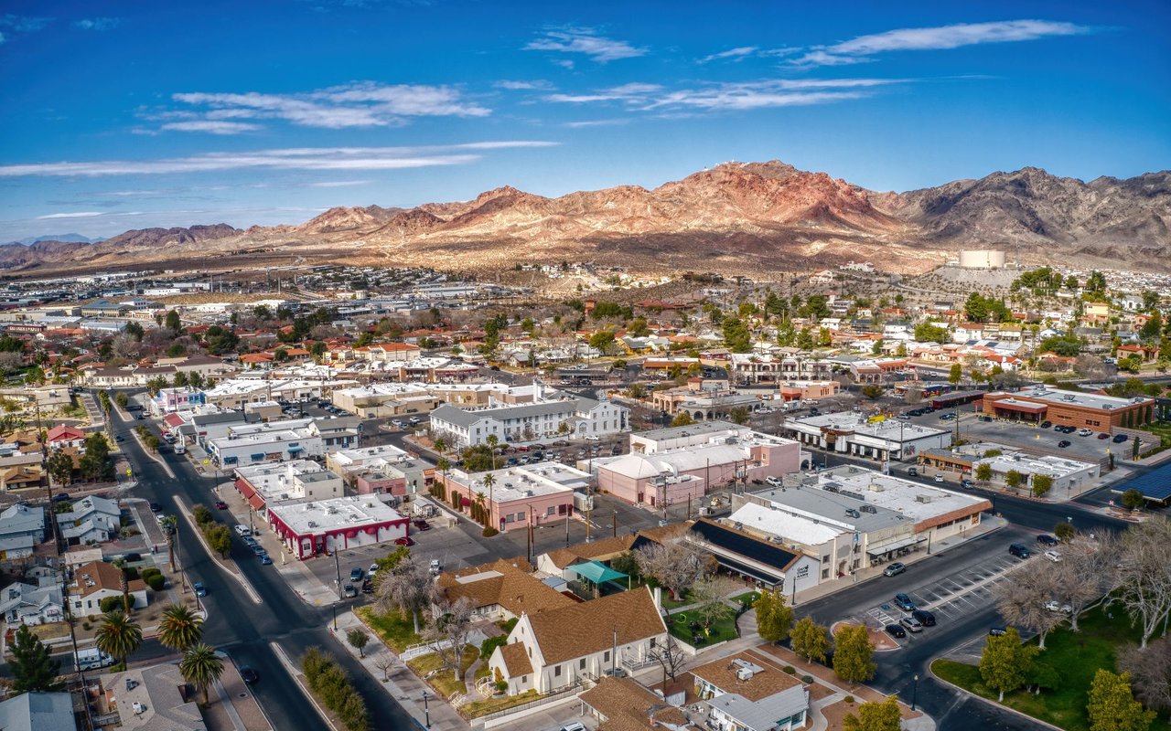 Aerial view of Boulder City, with low-rise buildings below rugged desert mountains.