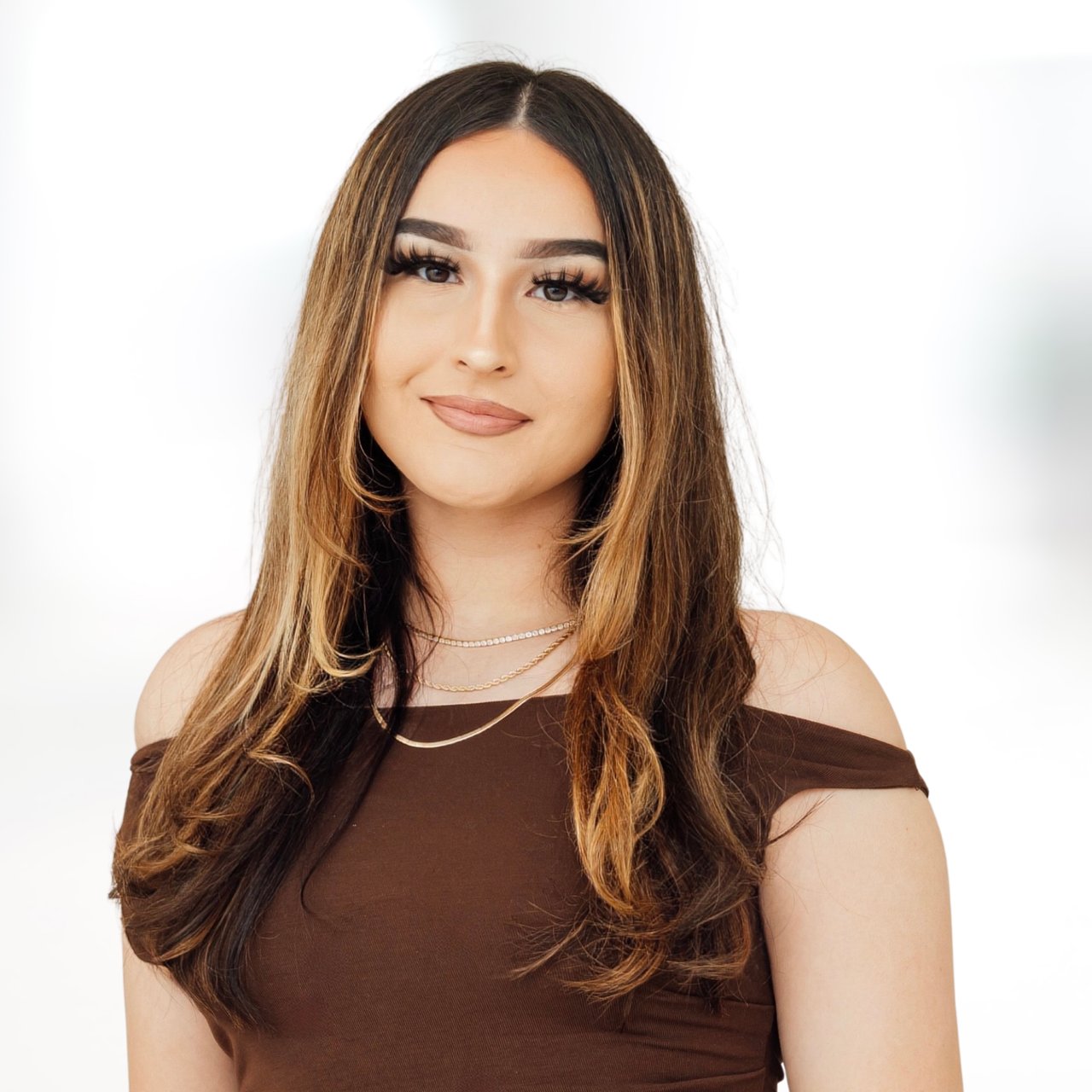 Jasmine Ludvigson in a brown off-the-shoulder top and layered gold necklaces.