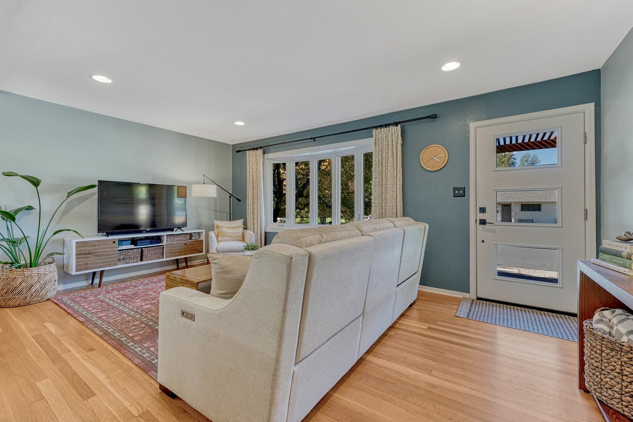 Living room inside the front entry, with hardwood floors, front windows and a modern glass-panel door