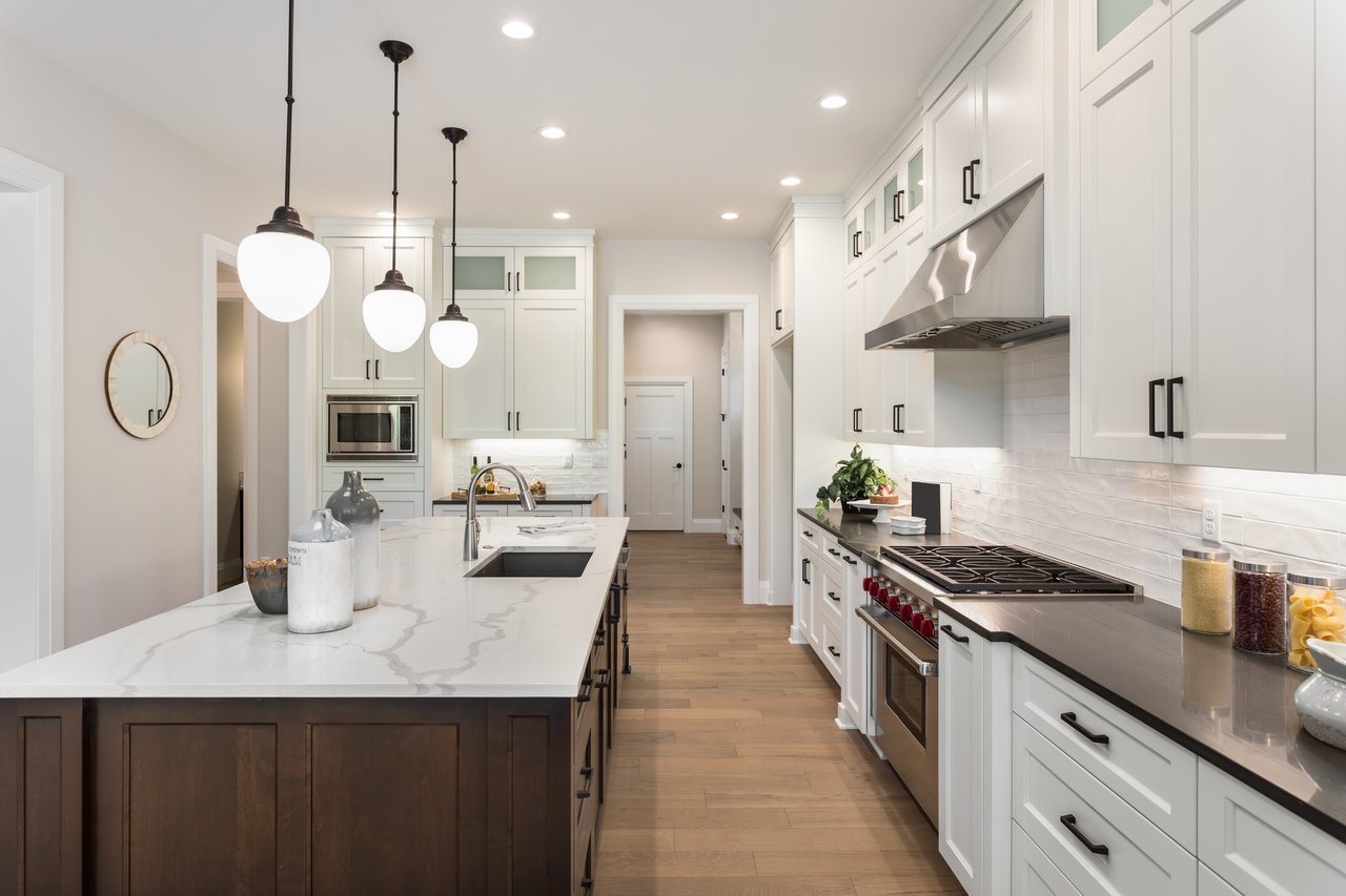 Modern kitchen with white cabinets, a marble-look island, and a long gas cooktop counter.
