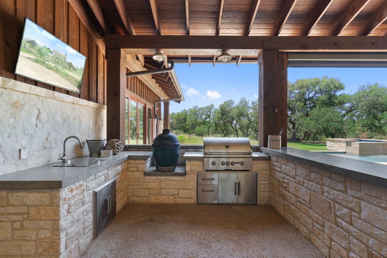 Outdoor kitchen at 335 Winning Colors with a built-in grill, sink, and stone surround beneath the covered patio.
