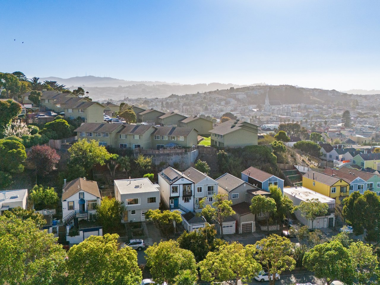 Drone aerial view overlooking a San Francisco neighborhood, showcasing residential streets and homes from above.