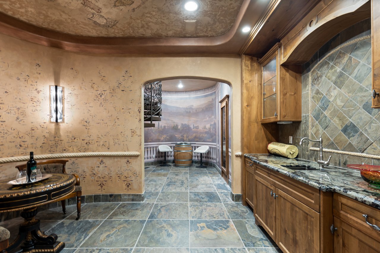 Wine-tasting room with wood cabinetry, stone tile, an ornate table, and a landscape mural.