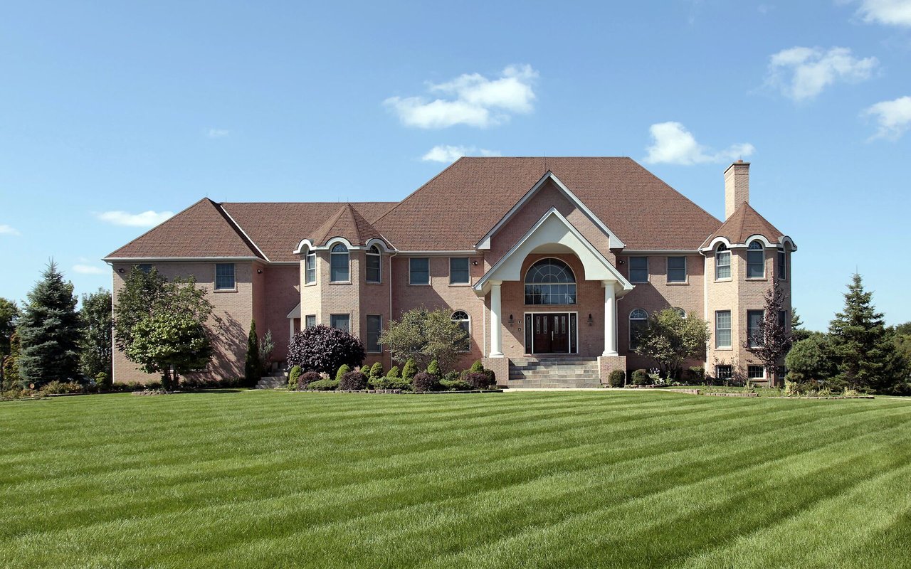 Large brick house with a columned entrance and broad, striped lawn.