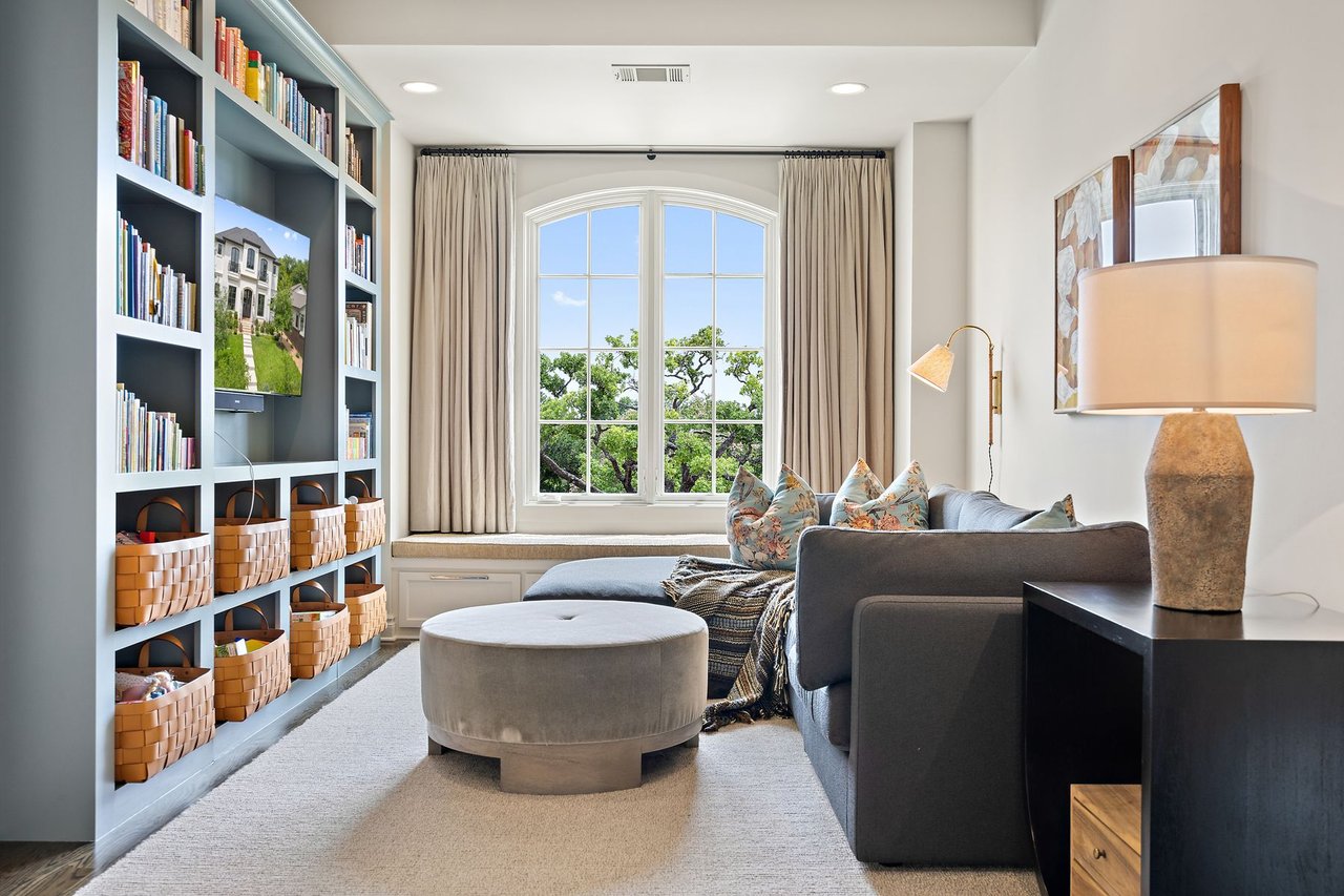 Family room with floor-to-ceiling built-in bookshelves and an arched window, furnished by Ashby Collective, at 2600 Westover Road in the Tarrytown neighborhood of Austin.