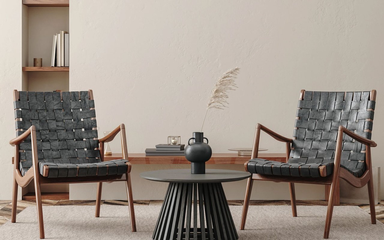 Two woven lounge chairs flank a round black coffee table in a neutral living room.