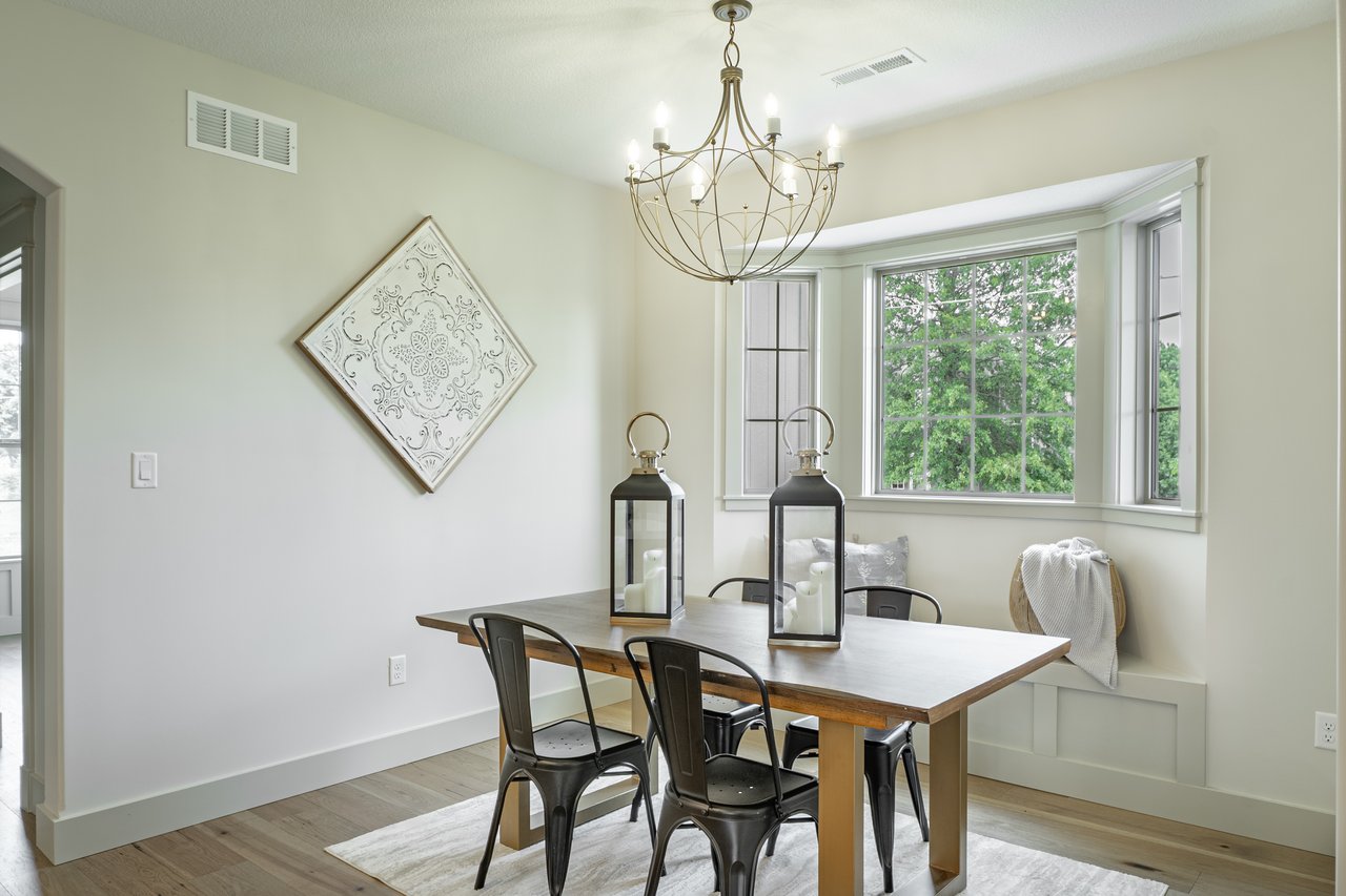 Dining room with a wooden table, chandelier, and bright bay window with built-in bench seating.
