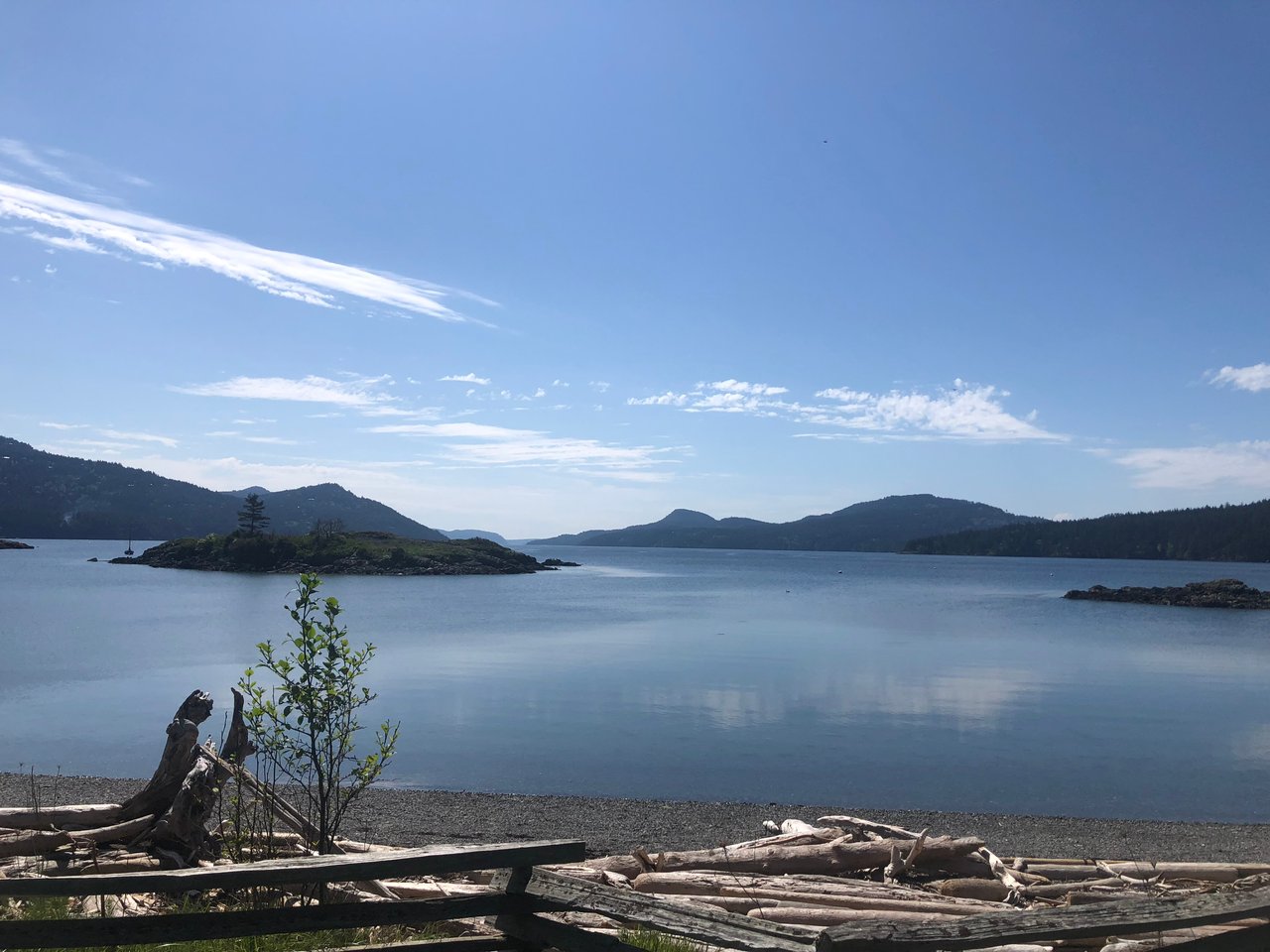 Orcas Island shoreline with driftwood on the beach and wooded islands across calm water