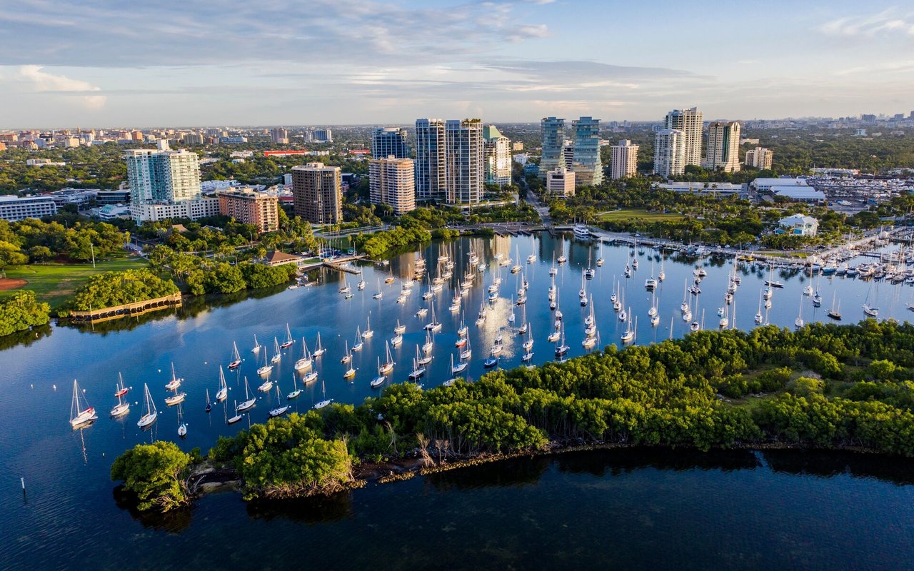 Aerial view of Coconut Grove marina, with sailboats, mangroves, and waterfront high-rises.